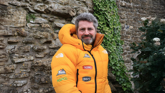 A male team member of the expedition team stood in his hiking jacket which has sponsor logos on it. 