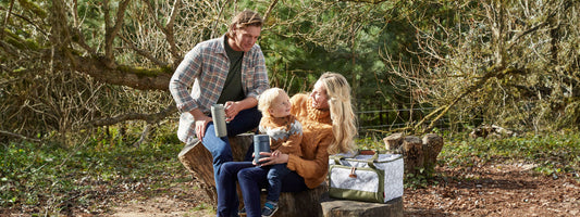 A young family having a picnic in the countryside using Thermos food flasks and Thermos travel mugs